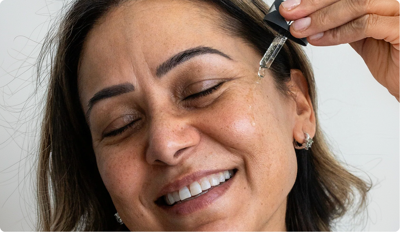 Woman applying Amrutini Luminosity Dewdrops serum