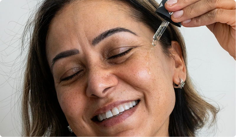 Woman applying Amrutini Luminosity Dewdrops serum